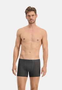 Boxer-briefs noirs avec une ceinture grise contrastante portant le nom de la marque. Texture lisse, design ajusté et longueur mi-cuisse.