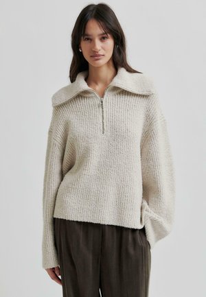 Beige, textured knit sweater with a wide collar and half-zip closure. Features loose fit and dropped shoulder seams.