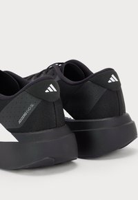 Un paio di scarpe da corsa Adidas Adizero Evo SL nere con suole spesse, logo visibile e pannelli laterali testurizzati, mostrate da un angolo posteriore.
