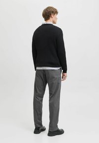 Czarny sweter z prążkowanego dzianiny, szare spodnie i czarne buty. Sweter ma okrągły dekolt. Prosty design, bez widocznych wzorów czy elementów metalowych.