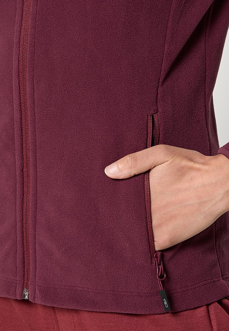 Bordeauxfarbener Fleece-Jacke mit durchgehendem Reißverschluss, seitlichen Reißverschlusstaschen und weichem Material. Sie zeigt ein glattes, angepasstes Design mit minimalen Akzenten.