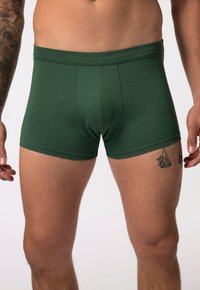 Boxer shorts en coton vert avec un design ajusté, taille élastique et texture lisse. Présente des coutures plates et de légers accents de marque.