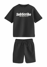 Sort bomuldsblandings t-shirt med korte ærmer og hvid tekst, parret med matchende shorts med elastisk talje og sidelommer.