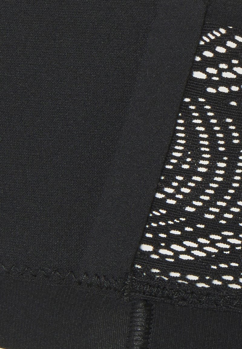 Primer plano de una tela negra con costura en zigzag y encaje negro adjunto con patrones florales blancos.