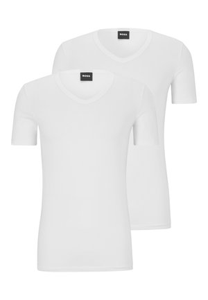 Dos camisetas blancas de manga corta, hechas de algodón y con un diseño de escote en V. Cada una tiene una textura suave y un estilo minimalista. Etiqueta negra visible.