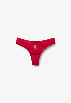 String bikini rouge en tissu côtelé, avec un motif brodé central représentant un renne de dessin animé avec des bois et une expression malicieuse.