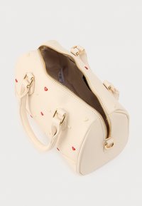 Μπεζ τσάντα χεριού από συνθετικό υλικό, με στρογγυλεμένο σχήμα, χρυστό φερμουάρ και ανάγλυφα μοτίβα καρδιάς σε κόκκινο και κρεμ χρώμα.