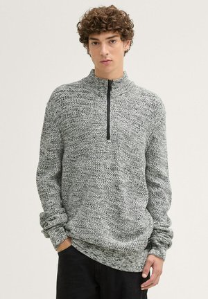 Grijze en zwarte gebreide quarter-zip pullover met een hoge kraag, geribde manchetten en een gestructureerd patroon. Stof lijkt warm en gezellig.