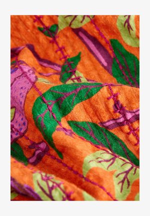 Tessuto dai colori vivaci con sfondo arancione, foglie verdi e accenti viola, con cuciture visibili in filo rosa e tessitura soffice.