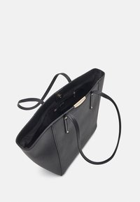 Sac cabas en cuir noir avec une forme structurée, deux poignées et des ferrures dorées ; intérieur avec une doublure lisse.