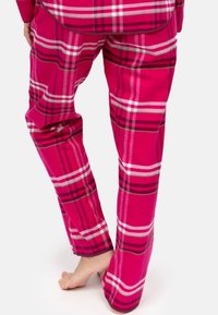 Pantalones de pijama de franela rosa con un gran patrón de cuadros en tonos de rosa, blanco y gris. Corte holgado con piernas rectas y una textura suave.