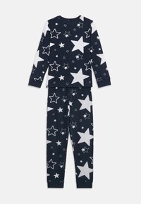 Navyblaues Schlafanzug-Set mit langärmeligem Oberteil und Hose, die mit weißen Sternmustern versehen ist. Hergestellt aus weichem Baumwollmaterial. Entspannter Schnitt.