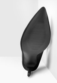 Scarpa nera con tacco alto, dalla superficie liscia e opaca e punta affusolata. Presenta una suola testurizzata con scanalature verticali per una migliore aderenza.