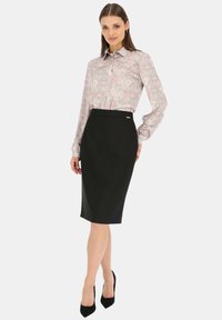 Bluzka w kwiatowy wzór w jasnoróżowym i szarym kolorze, zestawiona z dopasowaną czarną spódnicą ołówkową. Obie odzież mają gładką fakturę i dopasowany krój.