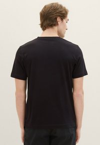 Zwart T-shirt met korte mouwen, ronde hals en een effen textuur, weergegeven vanaf de achterkant. Eenvoudig ontwerp zonder patronen of accenten.
