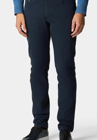 Chinos blu navy realizzati in misto cotone con una vestibilità slim, dotati di tasche frontali e sottili dettagli di cucitura. Abbinati a sneakers scure.