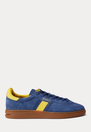 Blå ruskindssneaker med gule detaljer og brun sål, med Polo-logo på siden og Ralph Lauren-mærkning på sålen.