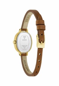 Montre en acier inoxydable doré avec un cadran rond blanc, un bracelet en cuir véritable marron et un design embossé signature à l'intérieur du bracelet.