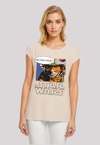 Beige t-shirt with short sleeves featuring a graphic of a character in an orange suit, text bubble saying "USE THE FORCE," and "STAR WARS" logo.