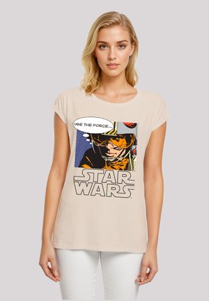Beige T-Shirt mit kurzen Ärmeln, das ein grafisches Motiv eines Charakters in einem orangenen Anzug zeigt, mit einer Sprechblase, die sagt "NUTZE DIE MACHT" und dem "STAR WARS"-Logo.