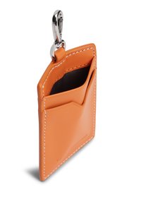 Πορτοκαλί δερμάτινη θήκη για κάρτες με λεία υφή, που διαθέτει ασημένιο κλιπ και δύο θήκες για κάρτες. Λευκή ραφή κατά μήκος των άκρων προσθέτει λεπτομέρεια.