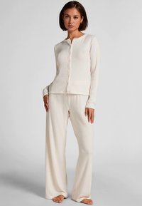 Cream-colored ribbed knit loungewear set featuring a button-down long-sleeve top and wide-leg pants, showcasing a soft texture.