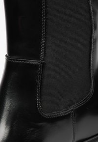 Stivaletto nero con esterno in pelle liscia, pannelli laterali elastici e punta arrotondata elegante. Una cucitura visibile arricchisce il design.
