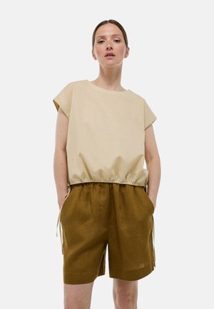 Haut beige à manches courtes avec une taille élastique, associé à un short marron avec poches latérales et liens ajustables. Design simple et décontracté.