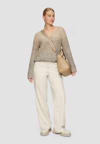 Beige gebreide trui met textuur, roomkleurige wijde broek, beige schoudertas met dunne band, en lichtgekleurde schoenen met dikke zool.