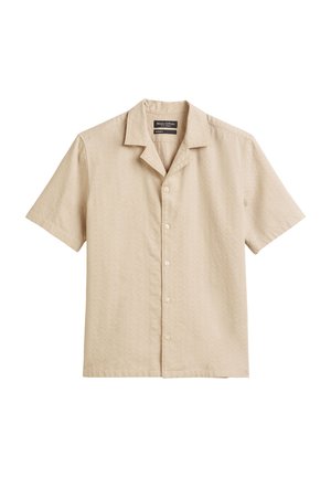Chemise à manches courtes en tissu beige clair, présentant un motif discret, un col en V et cinq boutons assortis sur le devant.