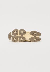 Semelle de chaussure avec une bande de roulement en caoutchouc beige et marron présentant des motifs d'adhérence en forme de losange et un design segmenté pour la traction.