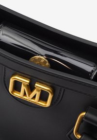 Sac à main en cuir noir avec une doublure intérieure brillante, de quincaillerie dorée et un logo en évidence à l'avant. Présente des détails texturés et une pièce de monnaie ronde.