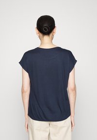 Top corto a maniche corte di colore blu navy con vestibilità comoda, collo rotondo e tessuto morbido. La parte posteriore presenta un orlo leggermente più lungo e maniche arrotolate.