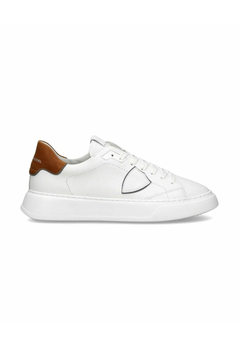 Hvide sneakers, læderoverdel med tan accents på hælen, perforeret design på siden, rund tå og hvid gummisål.