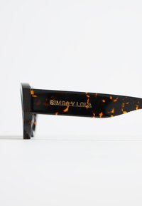 Gafas de sol carey con un acabado brillante, que cuentan con un marco audaz y el nombre de la marca "BIMBA Y LOLA" grabado en dorado en la patilla.