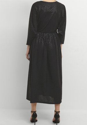 Abito lungo nero con texture a stampa leopardata, vita increspata e maniche lunghe. Il materiale appare leggero e leggermente trasparente.