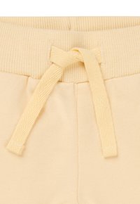 I pantaloni sportivi giallo chiaro presentano una vita a coste e un sistema di chiusura con cordoncino, con una texture morbida e tasche laterali per maggiore praticità.
