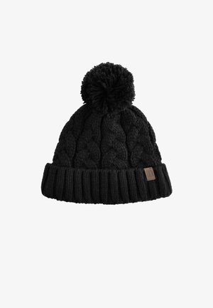 Schwarze gestrickte Wintermütze mit Zopfmuster, einer großen Bommel oben und einem umgeschlagenen, gerippten Bund mit kleinem braunem Logoetikett.