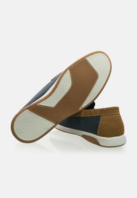 El zapato presenta una parte superior de malla azul marino y un talón de ante beige, con una suela de goma texturizada. La suela exterior tiene una base blanca con un patrón de diamantes para mayor agarre.