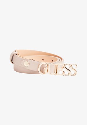 Ceinture en cuir beige clair avec boucle dorée "GUESS" et petit clou logo rond, enroulée sur fond blanc.