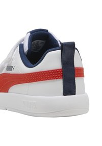 Scarpa sportiva bianca con una striscia rossa e dettagli in blu navy, dotata di una linguetta in tessuto testurizzato e un'etichetta sul tallone.