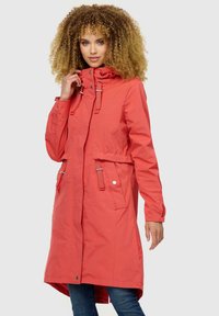 Abrigo impermeable color coral con capucha, herrajes plateados, cintura con cordón y dos bolsillos frontales. Textura suave con un diseño de longitud media.