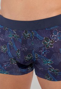 Navy blue boxer shorts with a floral pattern in light purple, teal, and green. Features a textured waistband with the brand name embossed.