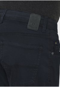 Dark blue jeans featuring a smooth texture and a leather patch labeled "redpoint" on the back, with visible stitching and pockets.