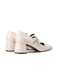 Scarpe in vernice beige con tacco a blocco, punta affilata e due cinturini regolabili con fibbie metalliche. Finitura liscia e design minimale.