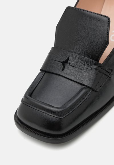 Mocassins en cuir noir avec un bout carré, finition texturée, une sangle décorative sur le cou-de-pied et de subtils détails de couture.
