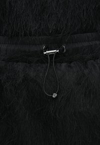 Czarny ubranie z teksturowanej, miękkiej tkaniny. Posiada zapięcie na ściągacz z czarnymi elementami oraz mały akcent dekoracyjny.