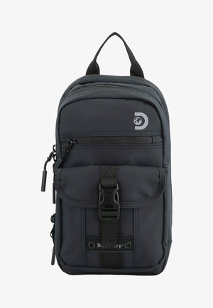 Mochila de tela negra con un bolsillo principal con cremallera, un bolsillo delantero con solapa asegurado por una hebilla y un logotipo de la marca. Textura suave y forma compacta.