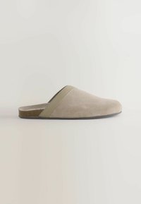 Bēšas zamšādas čības ar mīkstu, apaļu formu un kontrastējošu pelēku lenti pāri augšdaļai. Iekļauta plakanā zolīte ērtībai.