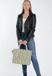 Polstret grøn tote taske med et diamantquiltet mønster, solide håndtag og en top lynlås lukning. Sat mod en lys baggrund.